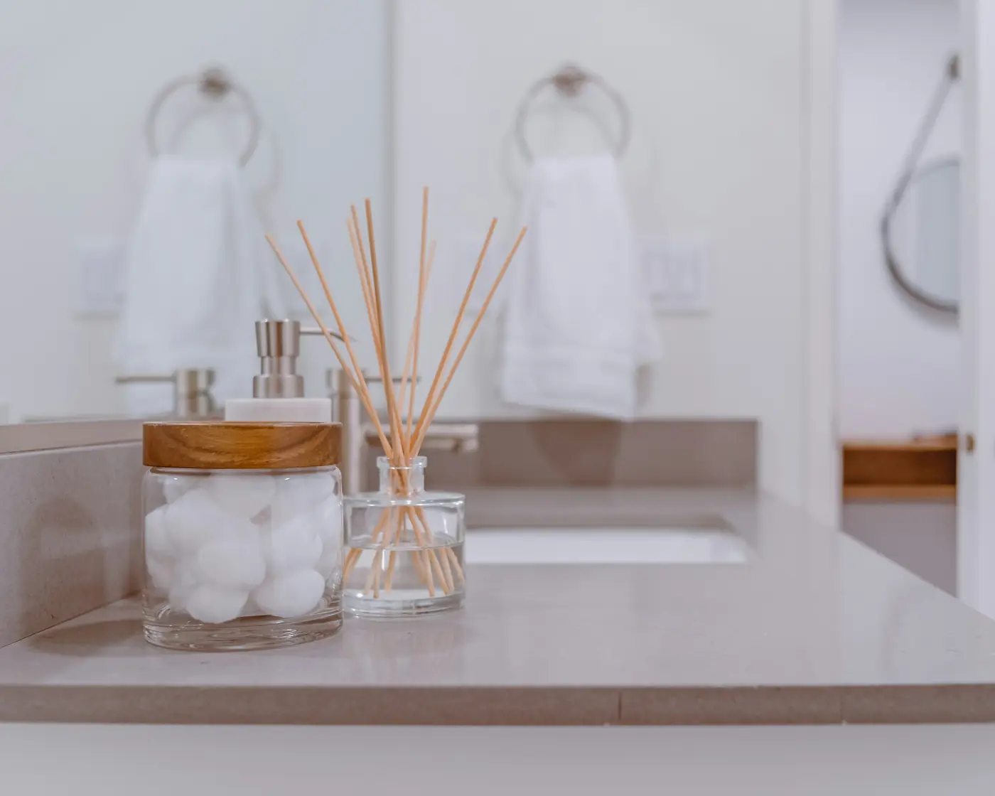 Folded white towels and a diffuser on a bathroom counter